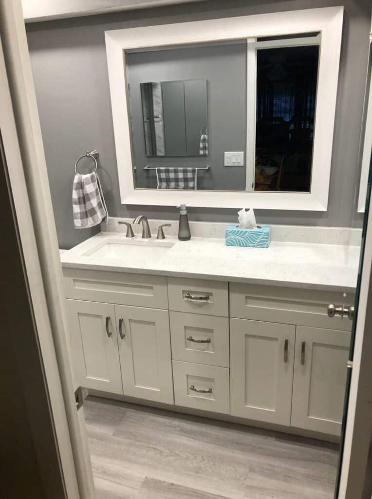 White bathroom vanity and mirror in a compact remodel