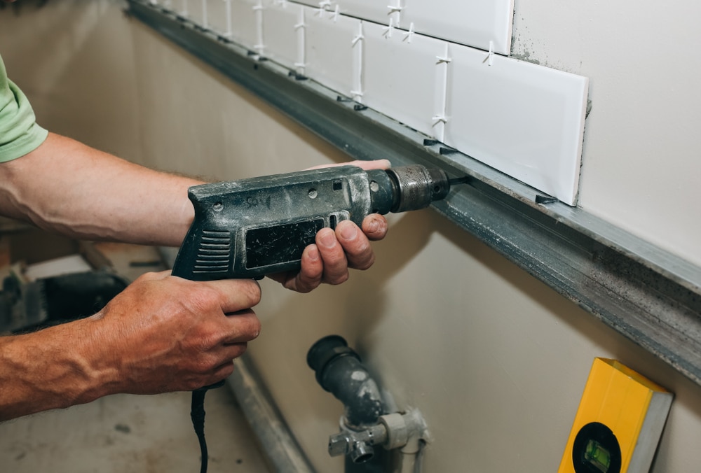 Contractor installing bathroom wall tile during a remodel