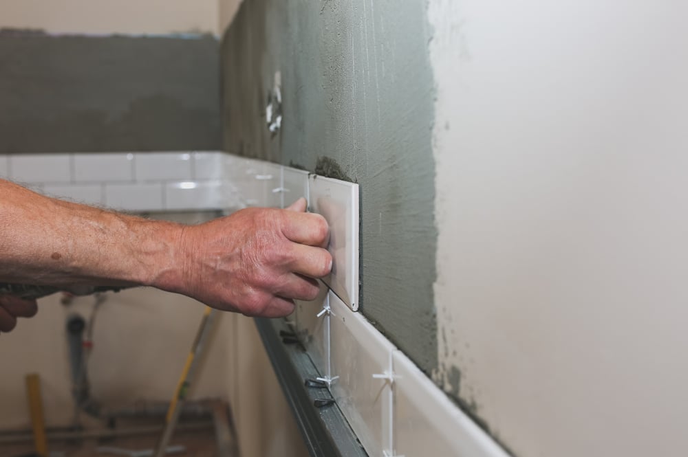 Contractor installing bathroom wall tile during a remodel