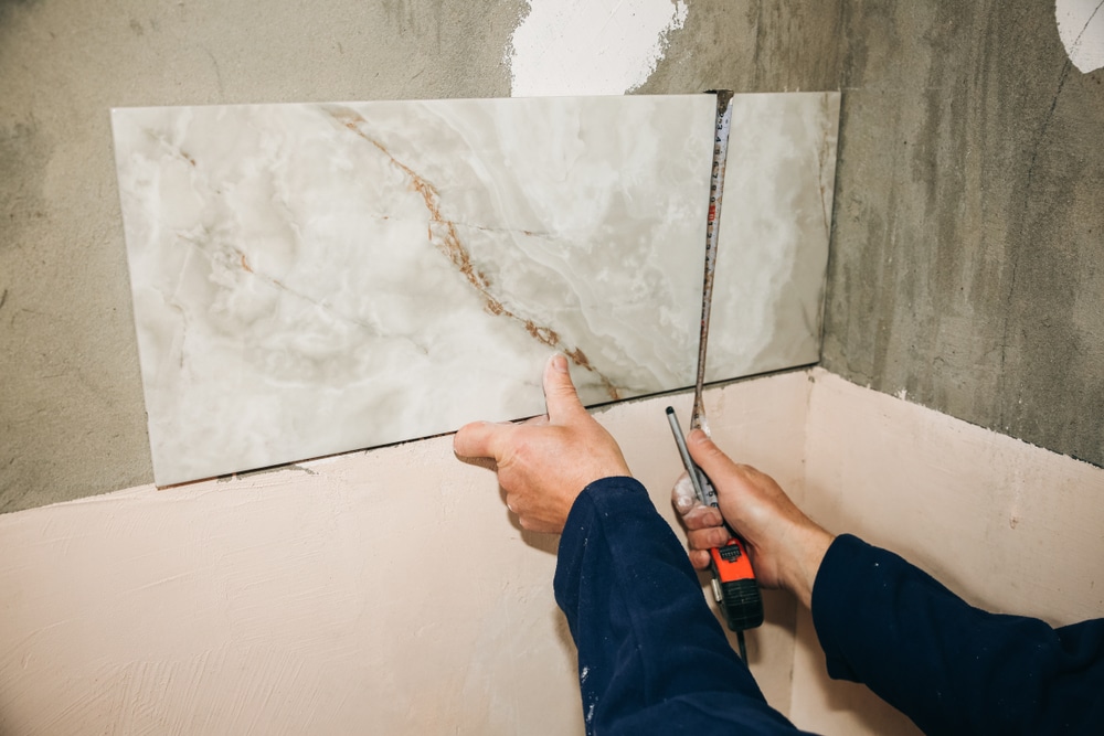 Contractor measuring tile during a bathroom remodel