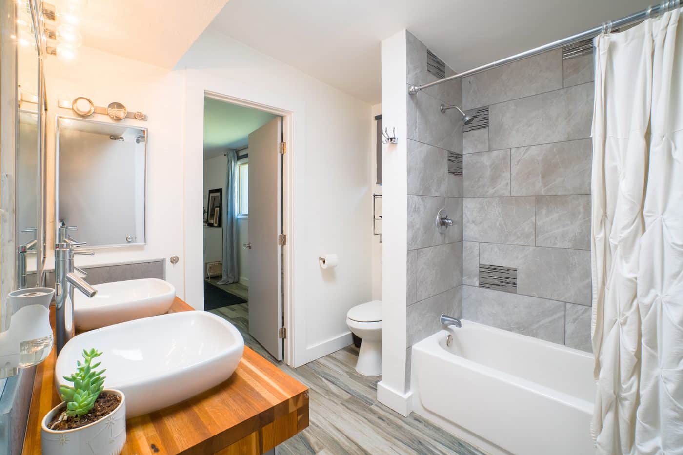 Modern bathroom remodel with vessel sinks and tiled tub surround