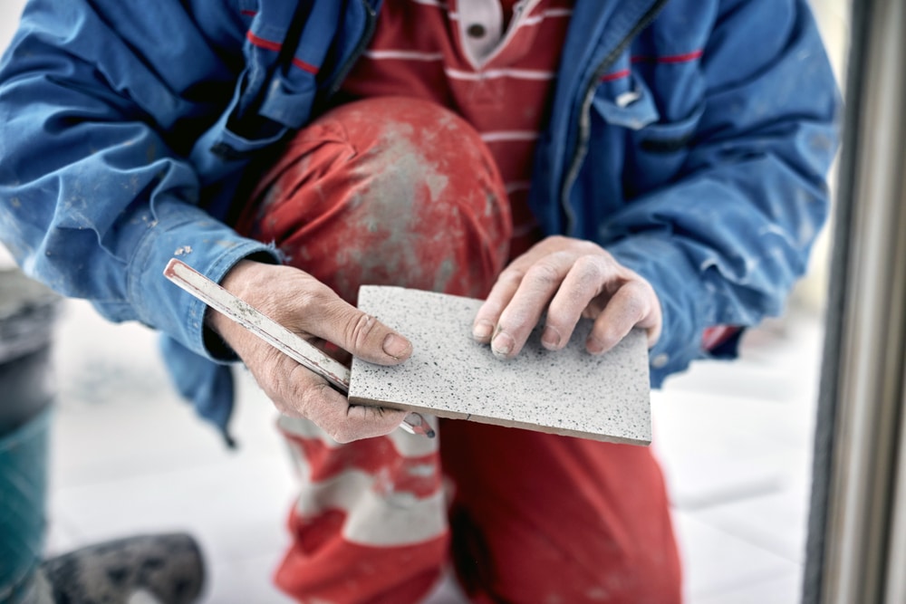 Tile installer placing new tile during a bathroom renovation