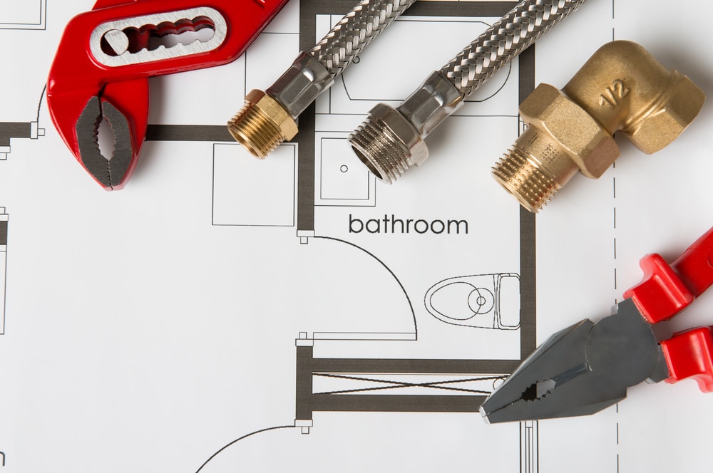 Plumbing tools on blueprint for bathroom remodeling cost planning