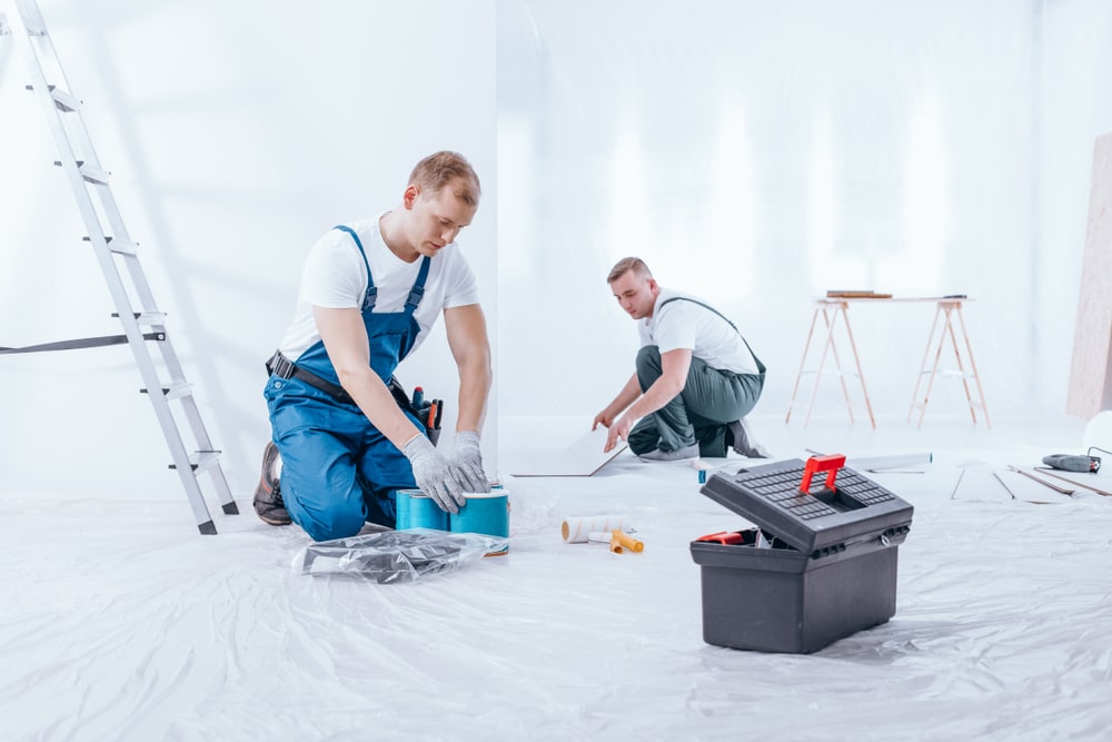 Painter preparing paints and expert arranging tiles on floor. Home renovation crew finishing interior